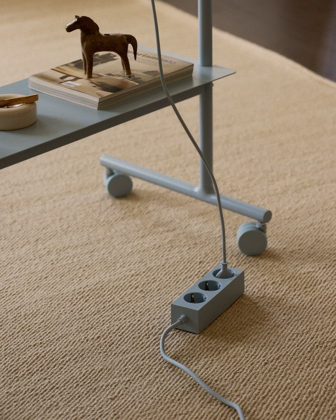 Rover in Powder Blue set på beigetæppe, detalje af hjul og stel med stikdåse og kabel på gulvet